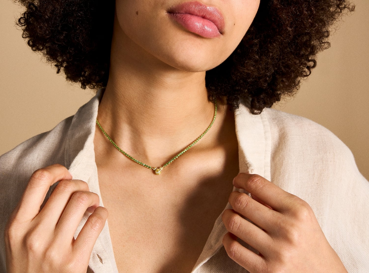 Image shows a woman wearing the necklace with a casual button down shirt. The necklace is shorter in length, just reaching her collarbone.