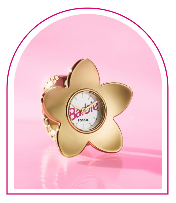 ピンクの背景に、Barbie™ Mansionをイメージした窓。窓の中に、Barbie™ x Fossil限定モデルのウォッチリング。ゴールドトーンの5枚の花弁がある花のデザイン、Barbieのロゴが付いたホワイトのダイヤル、指のサイズを選ばないフレキシブルバンドが特徴。
