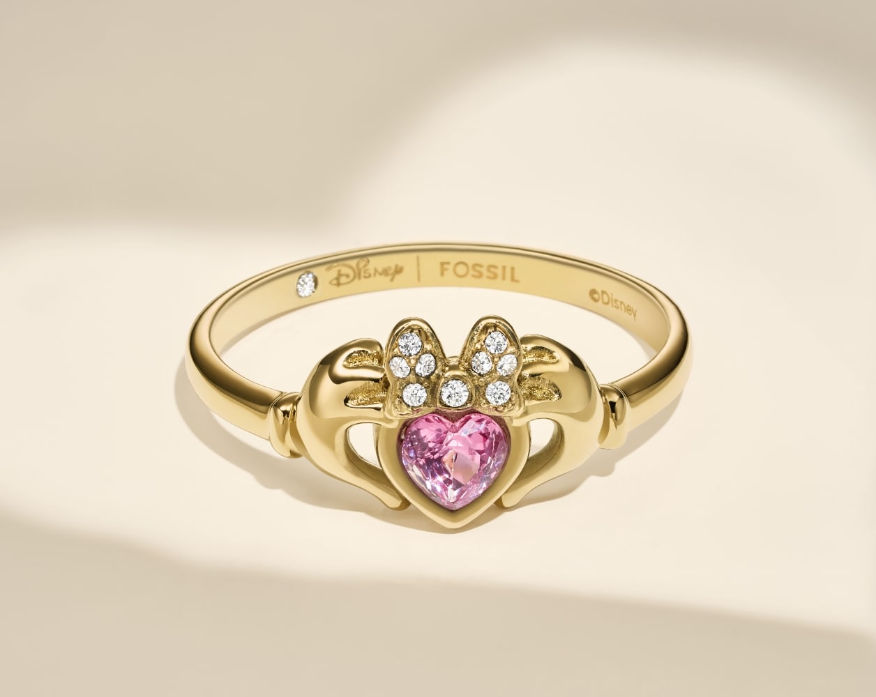 Der goldfarbene Claddagh-Ring Disney | Fossil mit rosafarbenem, herzförmigem Glasstein.