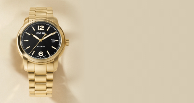 Gold Fossil watch on a beige background.
