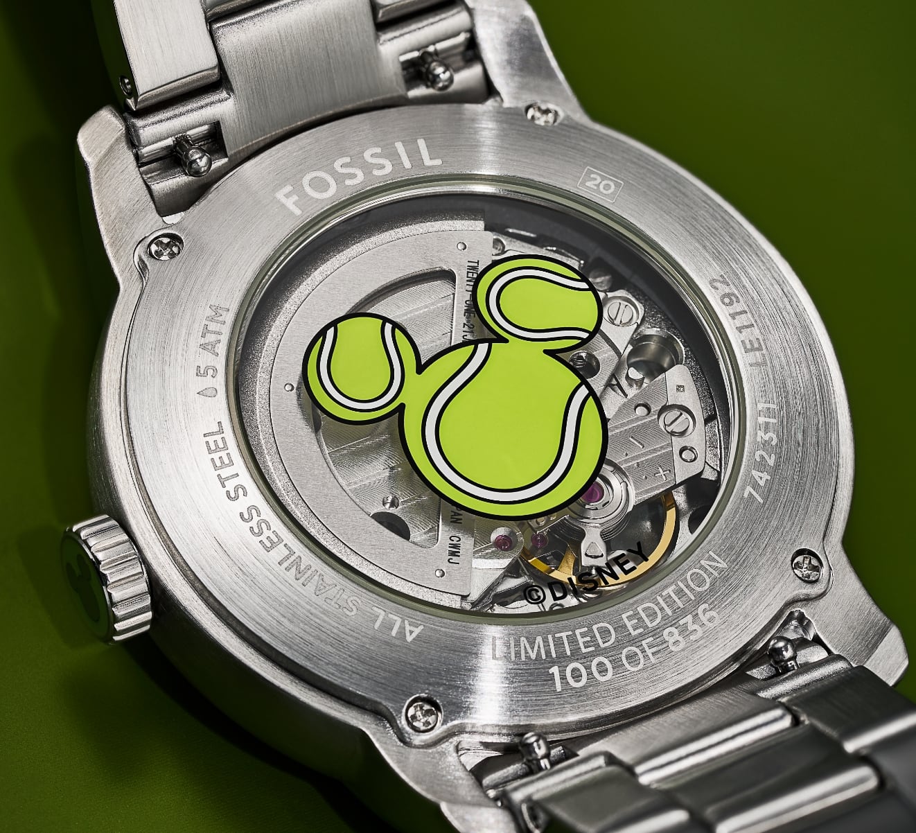 Un GIF de deux images montrant le dos et la couronne personnalisés de la montre, tous deux caractérisés par une silhouette de Mickey Mouse de Disney inspirée par les balles de tennis.