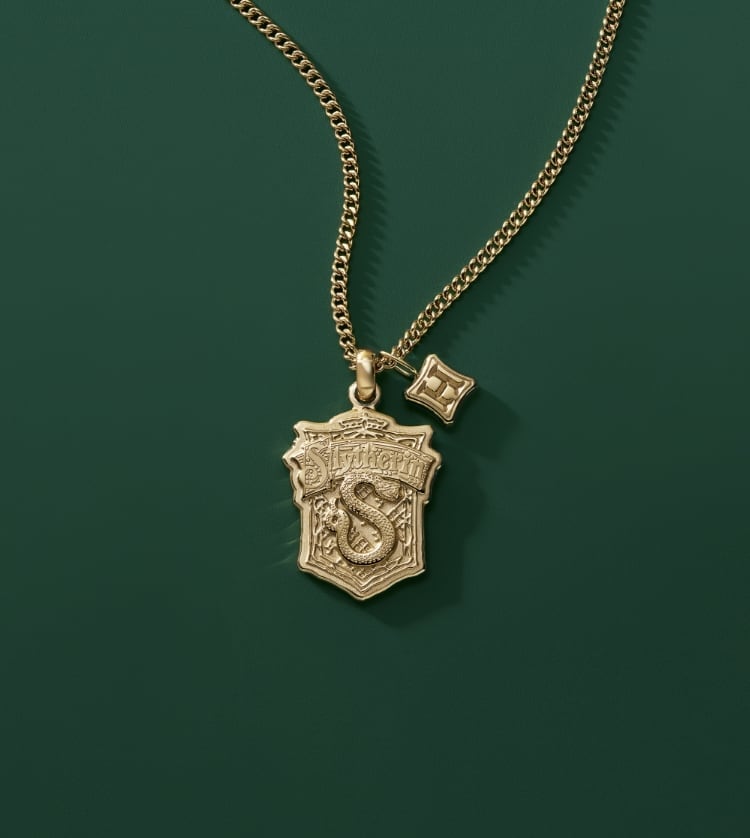 Silver-tone Slytherin house watch with a green and black strap and a gold-tone Slytherin house pendant.