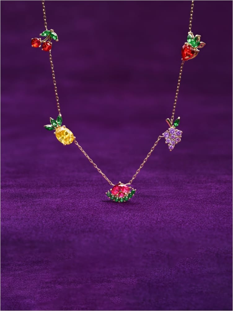 Un GIF mettant en vedette le collier ton or à cristaux colorés en forme de fruits et l’ensemble de cinq boucles d’oreilles à cristaux en forme de fruits.
