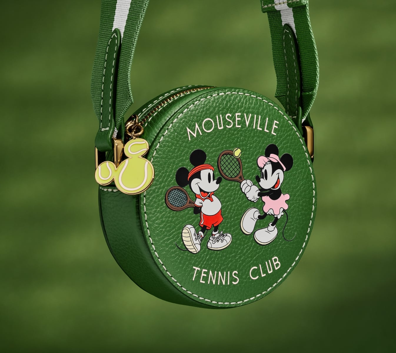 A closeup of our special-edition mini crossbody handbag, a round silhouette in green leather featuring a screenprinted graphic of Mickey and Minnie playing tennis.
